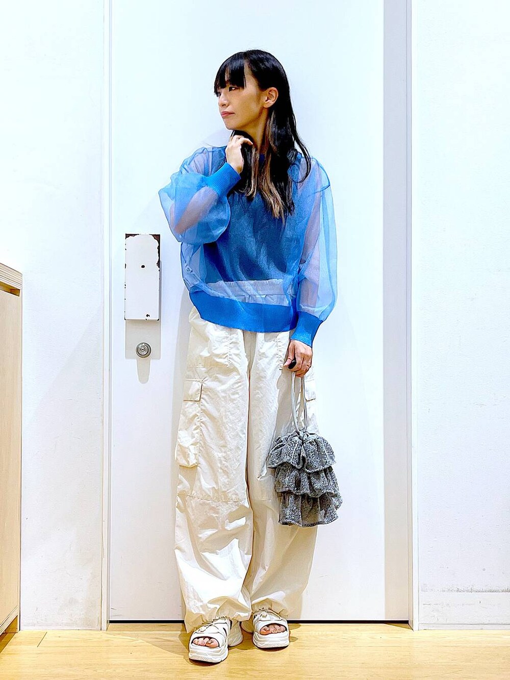 シルバー系のショルダーバッグ、ホワイト系のカーゴパンツ、ブラック系のニット/セーターを着用したレディースの夏コーディネートの2枚目の写真