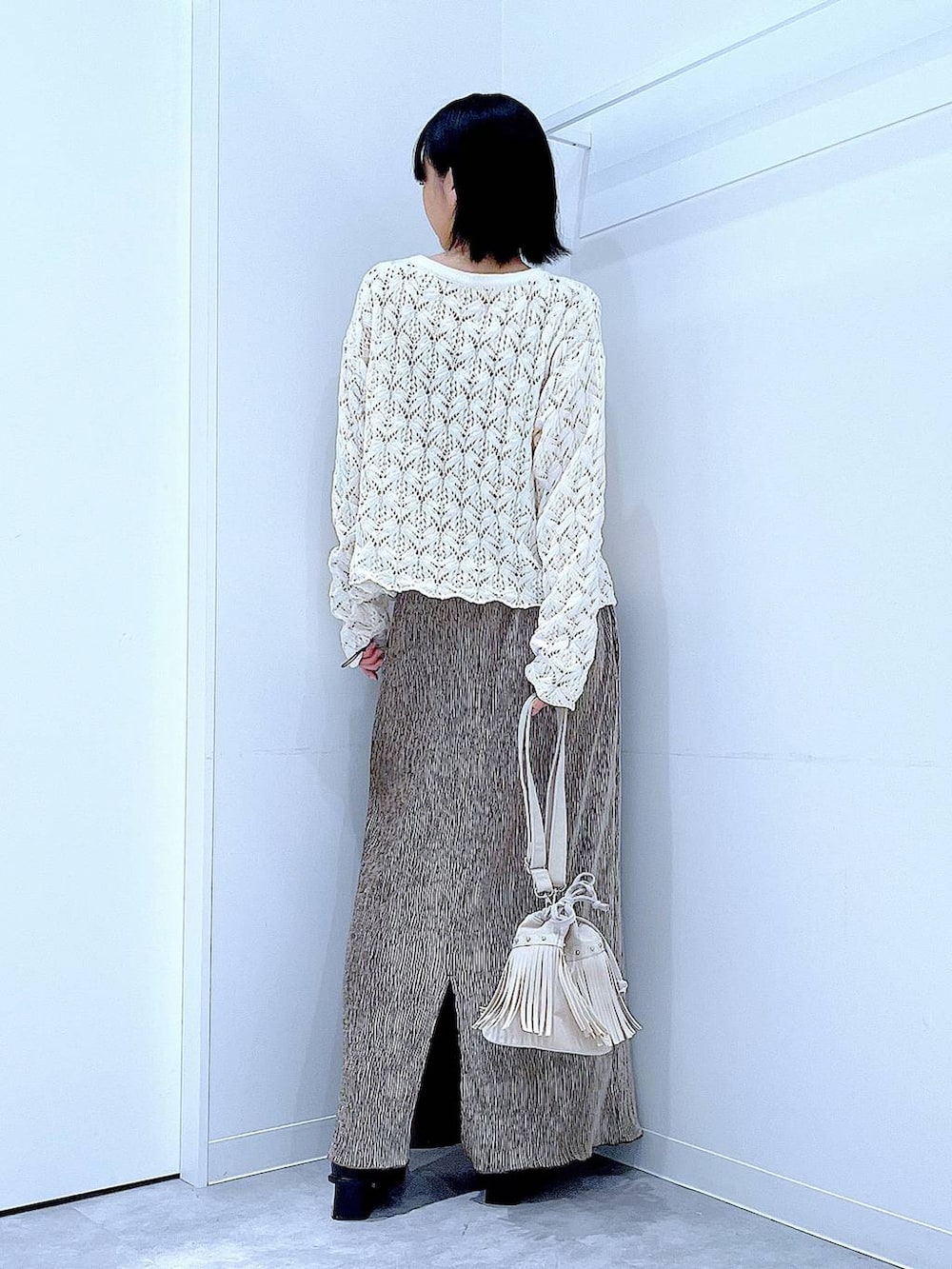 ブラック系のブーツ、ホワイト系のショルダーバッグ、ベージュ系のカーディガン/ボレロを着用したレディースの冬コーディネートの5枚目の写真