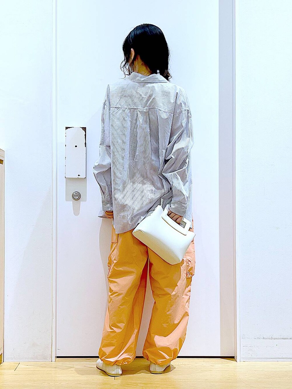 ホワイト系のシャツ/ブラウス、イエロー系のニット/セーター、ホワイト系のショルダーバッグを着用したレディースの春コーディネートの5枚目の写真