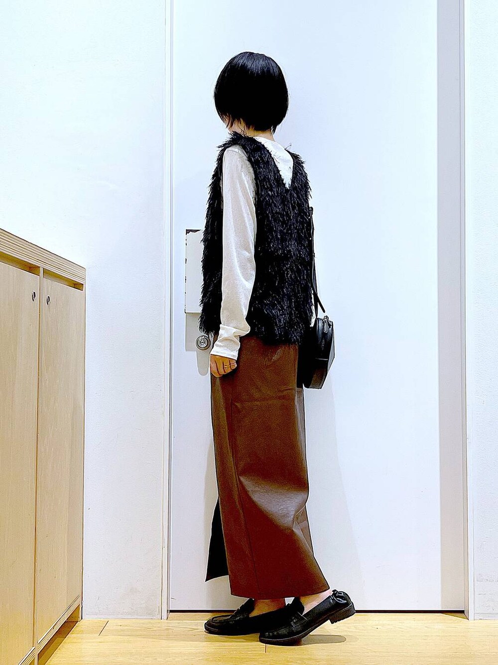 ブラウン系のスカート、ブラック系のショルダーバッグ、ホワイト系のTシャツ/カットソーを着用したレディースの秋コーディネートの3枚目の写真