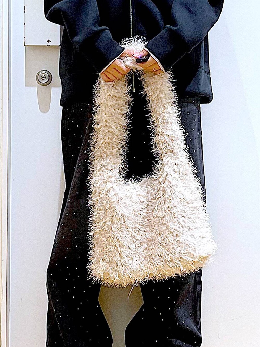 ベージュ系のスリッポン、ベージュ系のショルダーバッグ、ブラック系のデニムパンツを着用したレディースの冬コーディネートの9枚目の写真