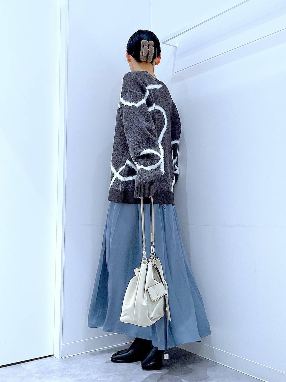 ブラック系のブーツ、グレー系のニット/セーター、ブラウン系のバレッタ/ヘアクリップを着用したレディースの冬コーディネートの3枚目の写真