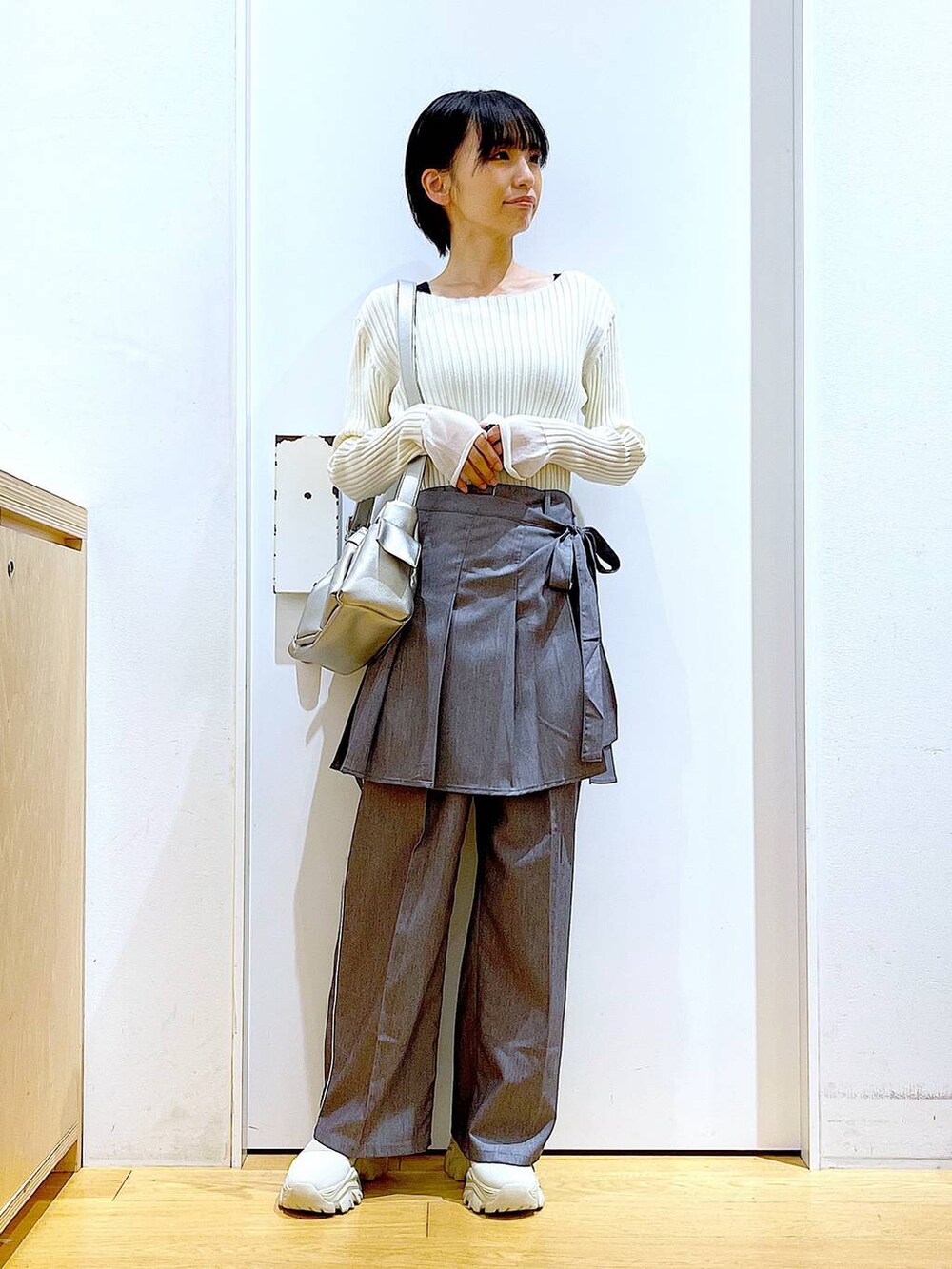 ホワイト系のニット/セーター、グレー系のスラックス、グレー系のスカートを着用したレディースの秋コーディネートの2枚目の写真