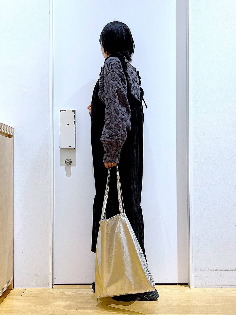 シルバー系のトートバッグ、ブラック系のブーツ、グレー系のニット/セーターを着用したレディースの冬コーディネートの3枚目の写真