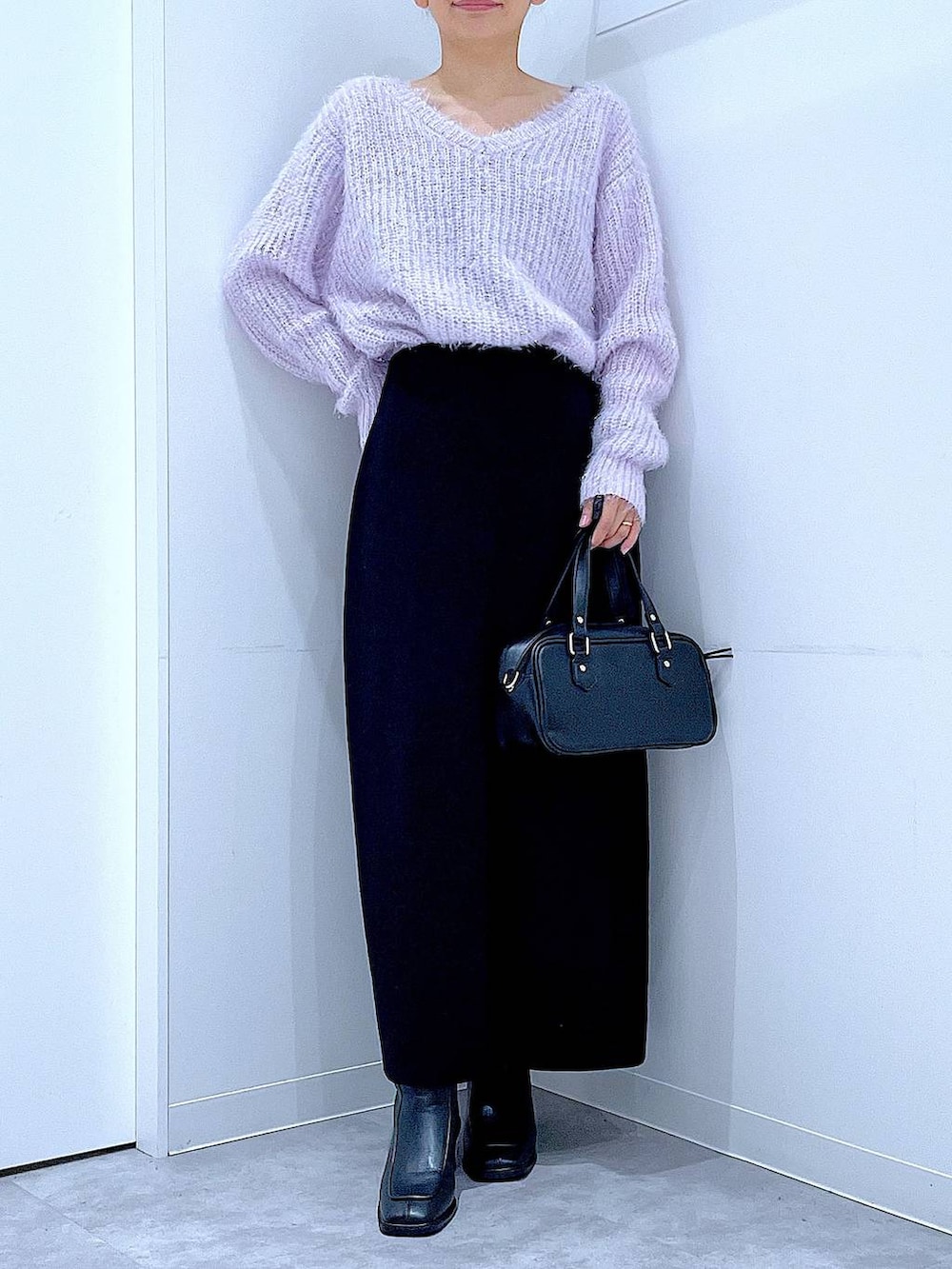 ブラック系のブーツ、ブラック系のショルダーバッグ、ブラック系のスカートを着用したレディースの冬コーディネートの6枚目の写真