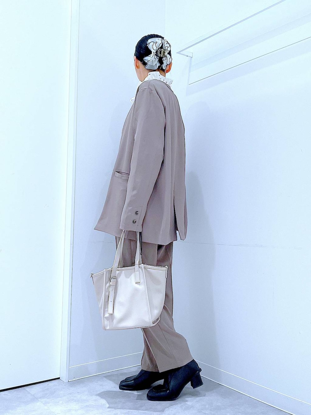 ブラック系のブーツ、グレー系のトートバッグ、ブラウン系のノーカラージャケットを着用したレディースの冬コーディネートの3枚目の写真