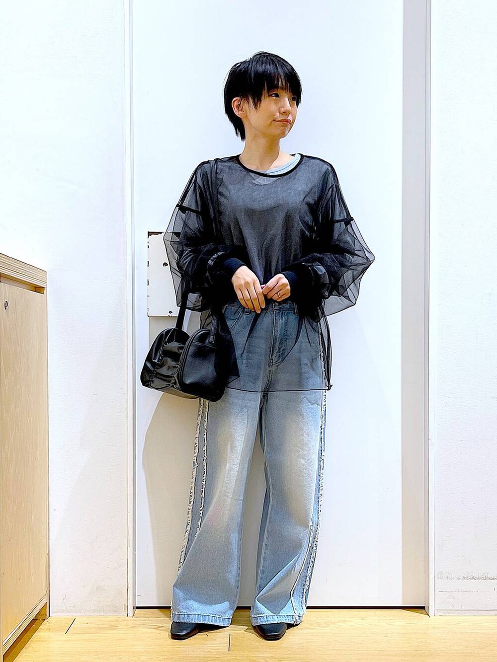 ブラック系のショルダーバッグ、ブラック系のパンプス、ブルー系のデニムパンツを着用したレディースの春コーディネートの2枚目の写真