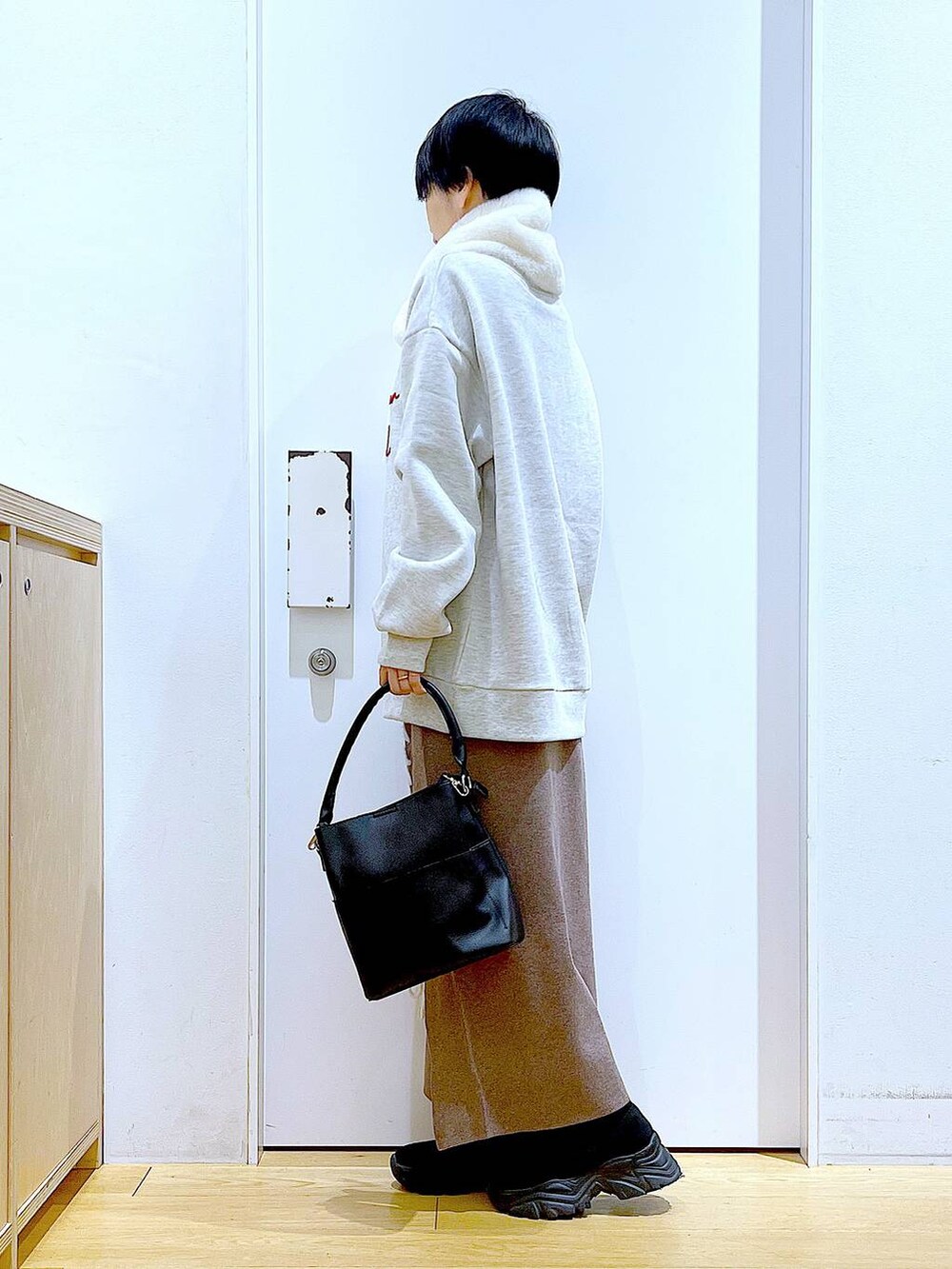 ブラック系のショルダーバッグ、ブラック系のブーツ、ブラウン系のスカートを着用したレディースの冬コーディネートの3枚目の写真