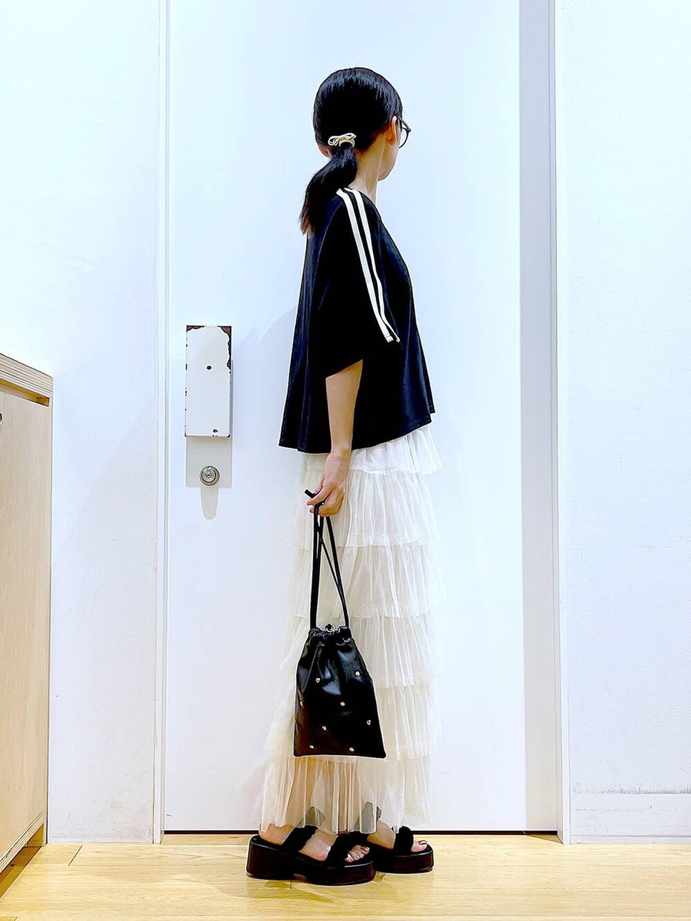 ブラック系のサンダル、ブラック系のショルダーバッグ、ベージュ系のスカートを着用したレディースの夏コーディネートの4枚目の写真