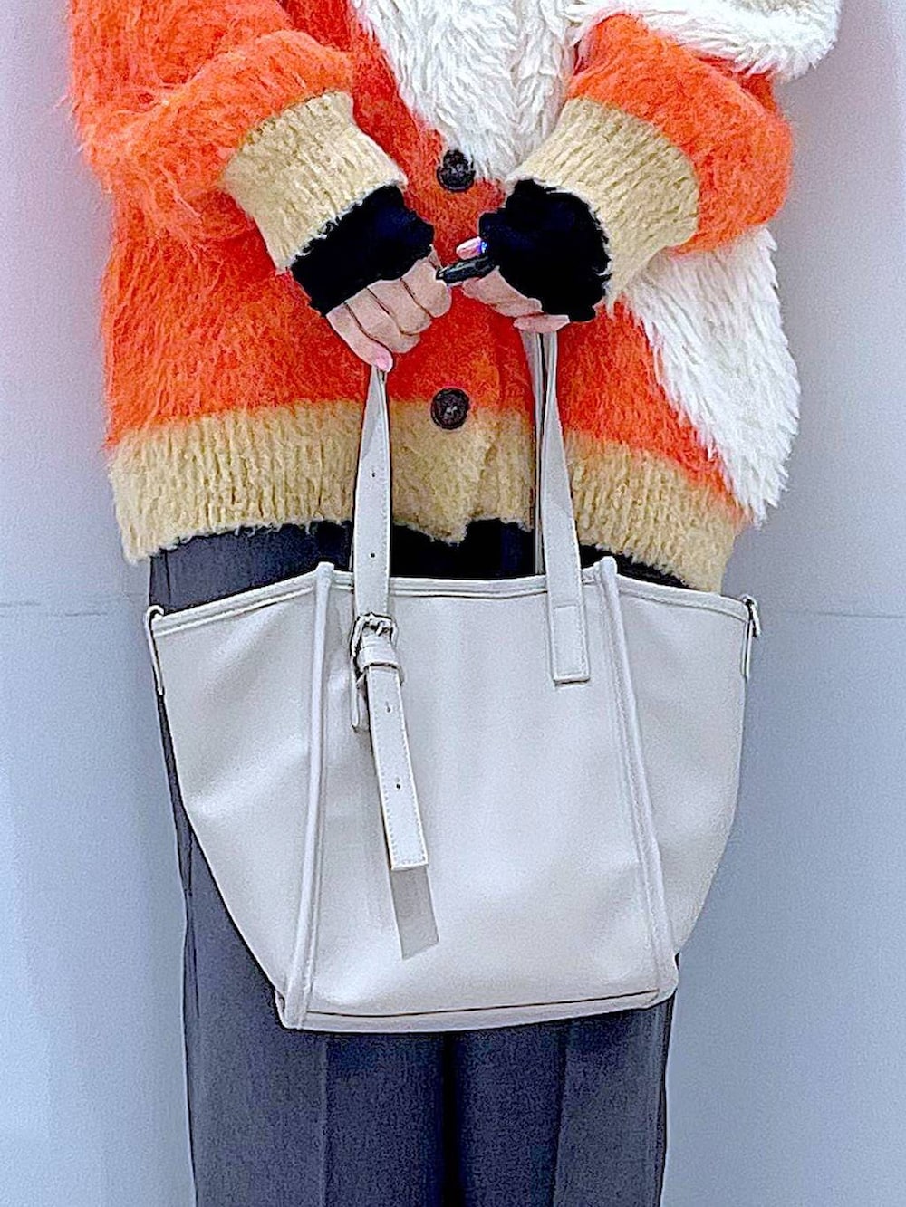 オレンジ系のカーディガン/ボレロ、ブラック系のブーツ、グレー系のスラックスを着用したレディースの冬コーディネートの9枚目の写真