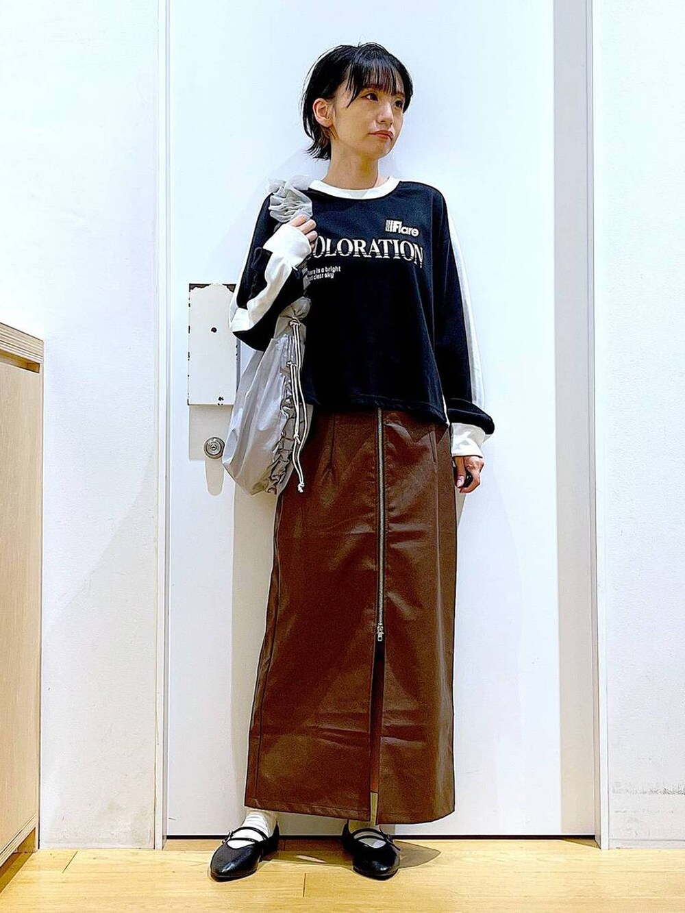 ブラウン系のスカート、ブラック系のパンプス、グレー系のショルダーバッグを着用したレディースの秋コーディネートの2枚目の写真