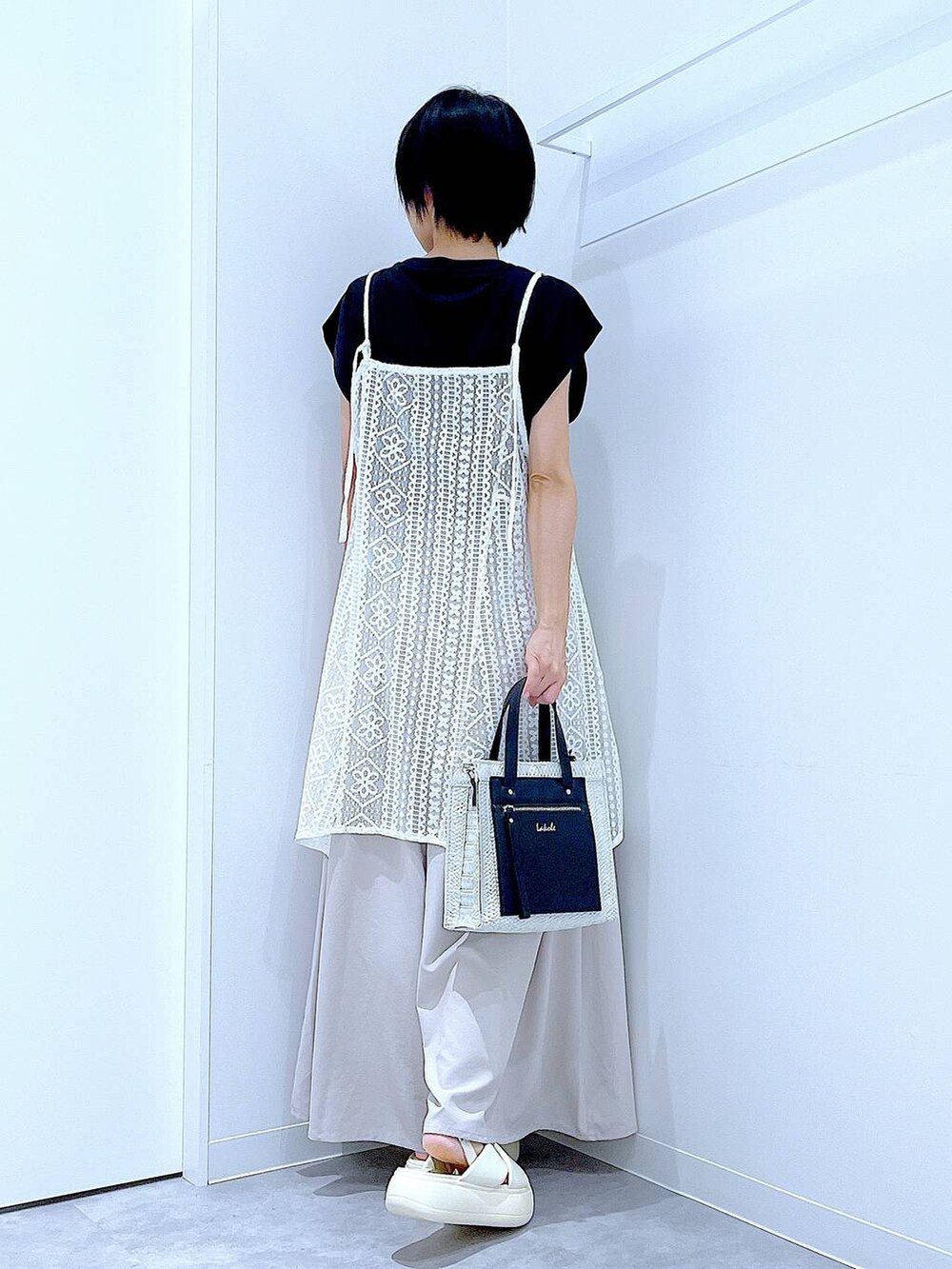 ホワイト系のショルダーバッグ、ホワイト系のサンダル、ブラック系のTシャツ/カットソーを着用したレディースの夏コーディネートの5枚目の写真