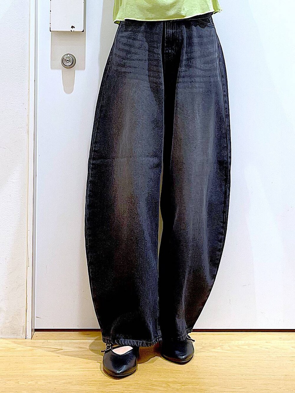 グリーン系のTシャツ/カットソー、ブラック系のデニムパンツ、ブラック系のパンプスを着用したレディースの秋コーディネートの8枚目の写真