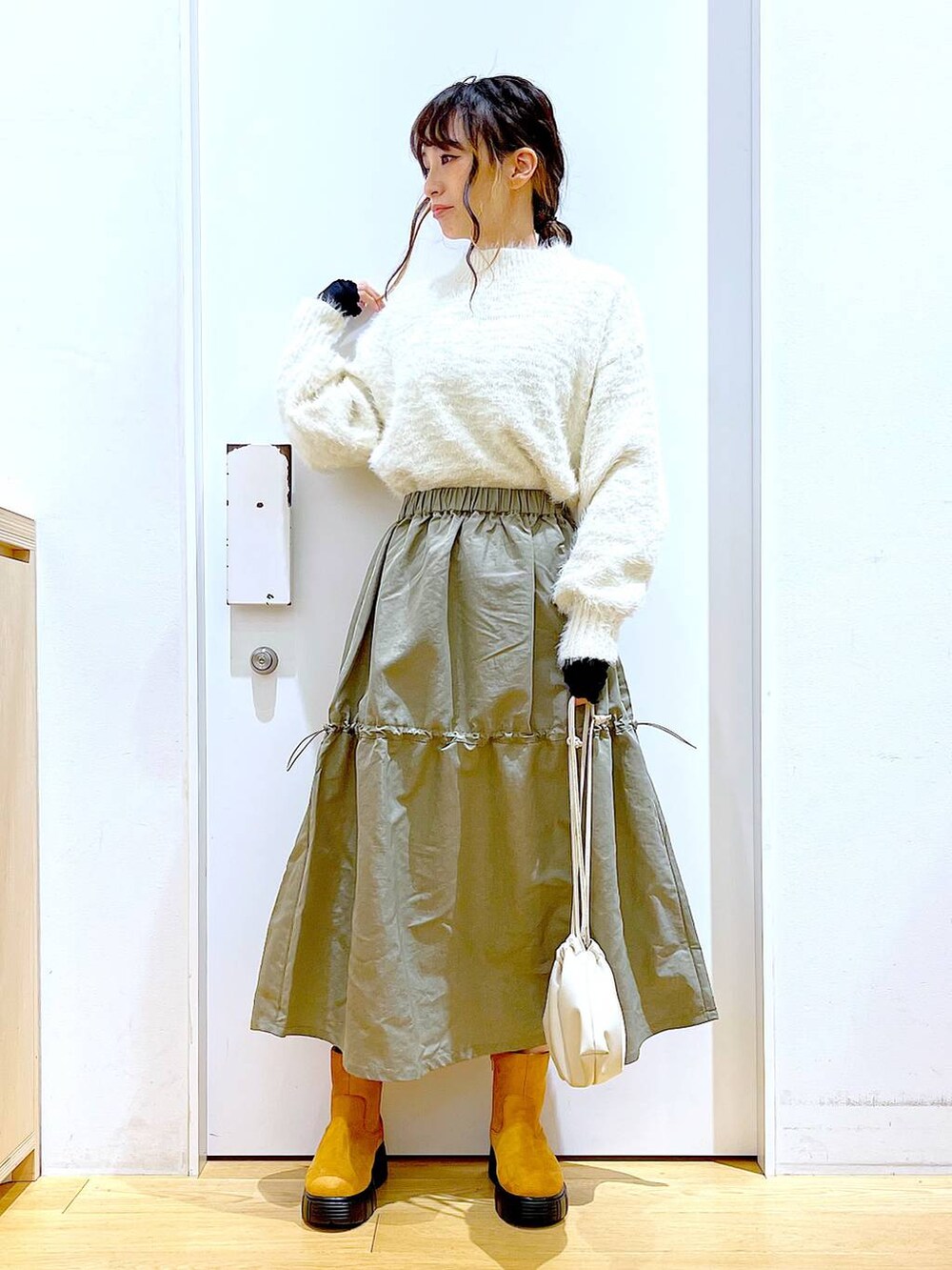 ベージュ系のショルダーバッグ、ベージュ系のブーツ、ベージュ系のニット/セーターを着用したレディースの冬コーディネートの2枚目の写真