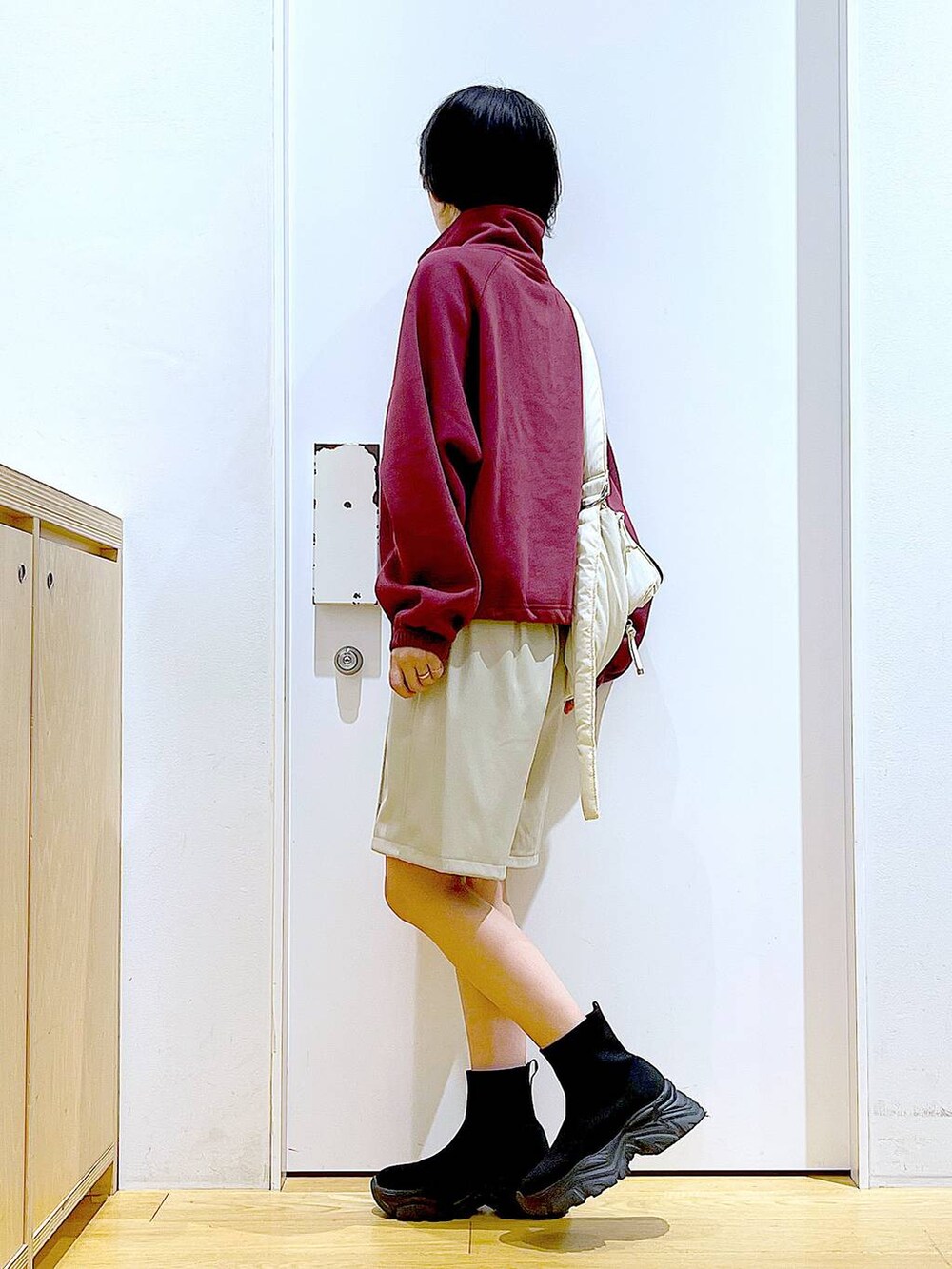 ホワイト系のショルダーバッグ、ブラック系のブーツ、レッド系のスウェットを着用したレディースの冬コーディネートの3枚目の写真