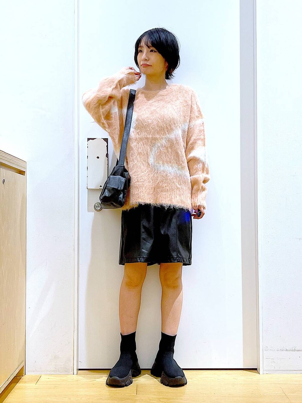 ピンク系のニット/セーター、ブラック系のブーツ、ブラック系のショルダーバッグを着用したレディースの冬コーディネートの2枚目の写真