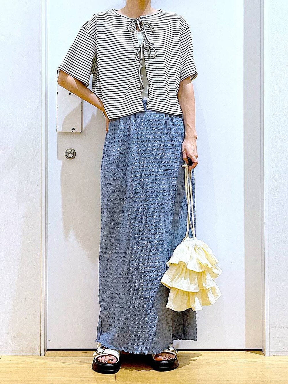 ホワイト系のサンダル、ブルー系のスカート、ホワイト系のショルダーバッグを着用したレディースの秋コーディネートの6枚目の写真