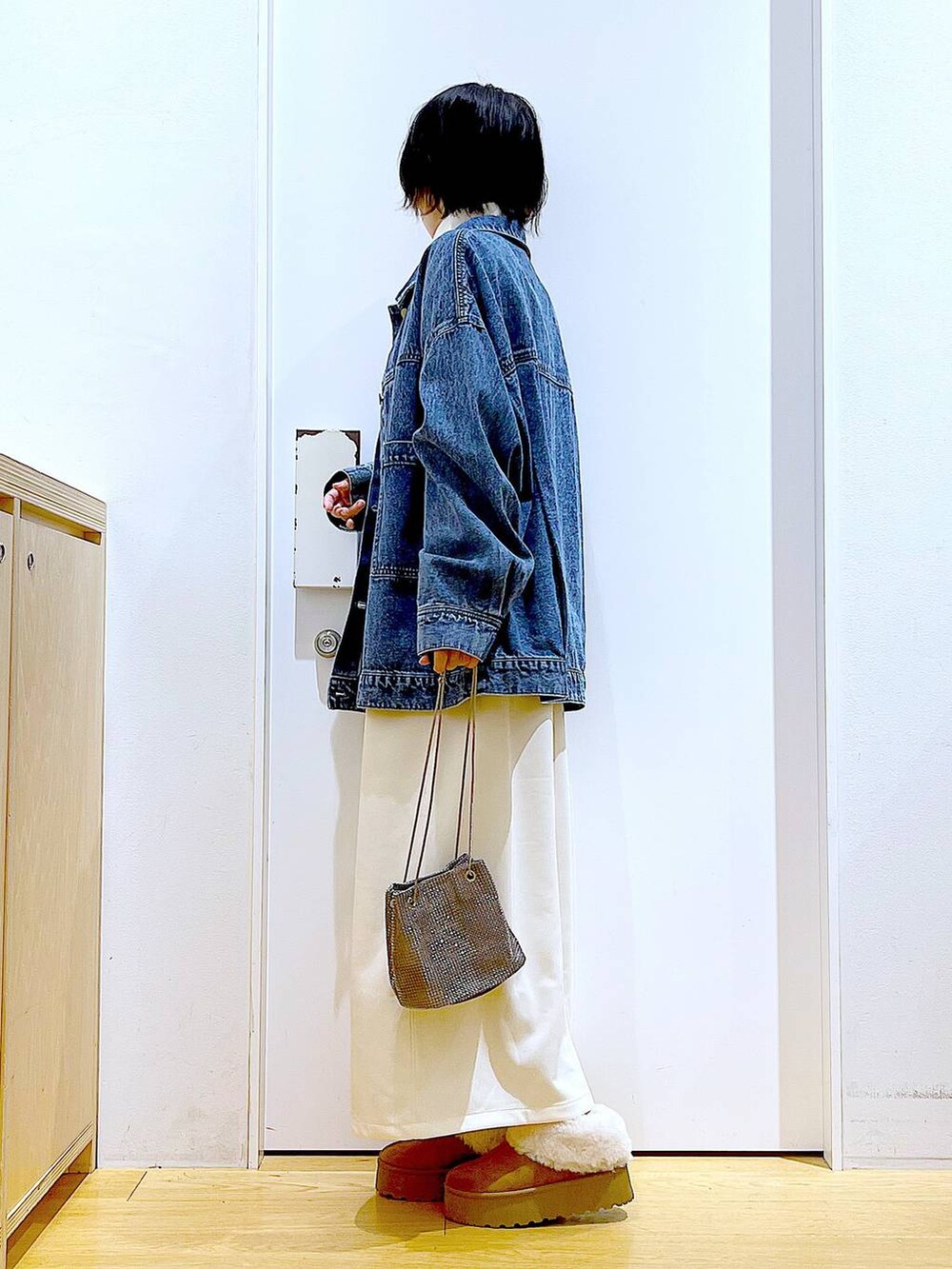 グレー系のショルダーバッグ、ベージュ系のワンピース、ベージュ系のスリッポンを着用したレディースの秋コーディネートの3枚目の写真