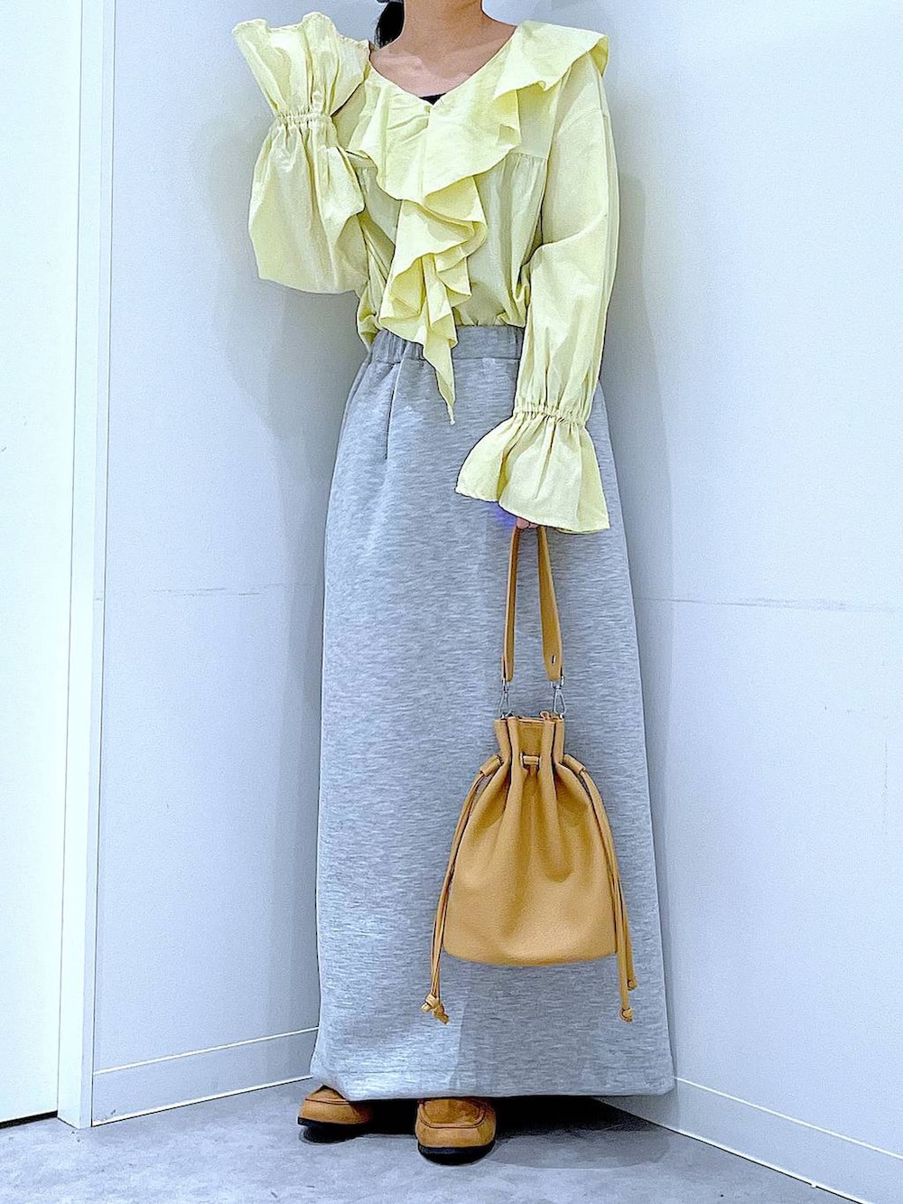 グレー系のスカート、ベージュ系のローファー、ブラウン系のショルダーバッグを着用したレディースの冬コーディネートの6枚目の写真