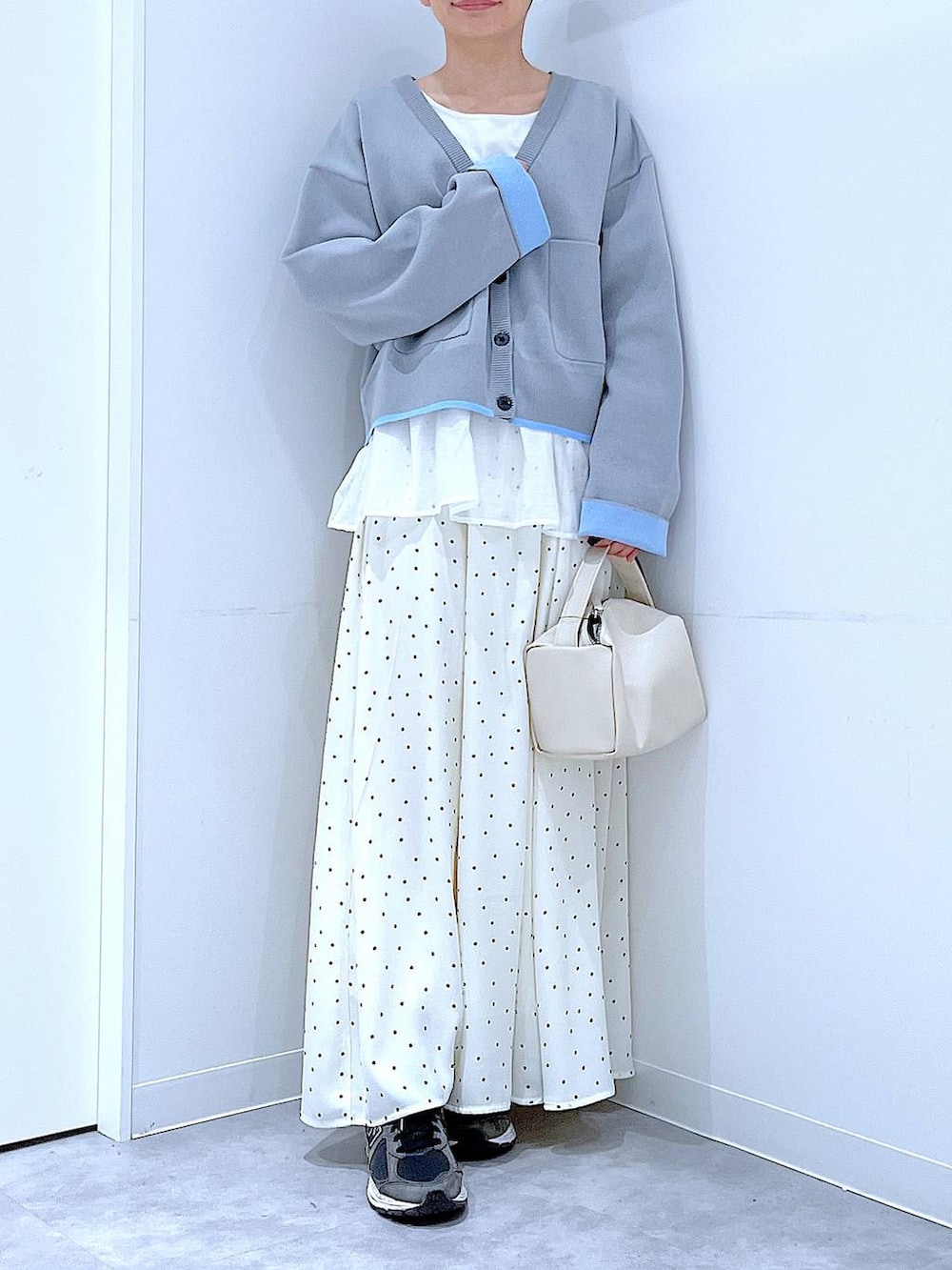 ホワイト系のショルダーバッグ、グレー系のカーディガン/ボレロ、ホワイト系のスカートを着用したレディースの春コーディネートの6枚目の写真