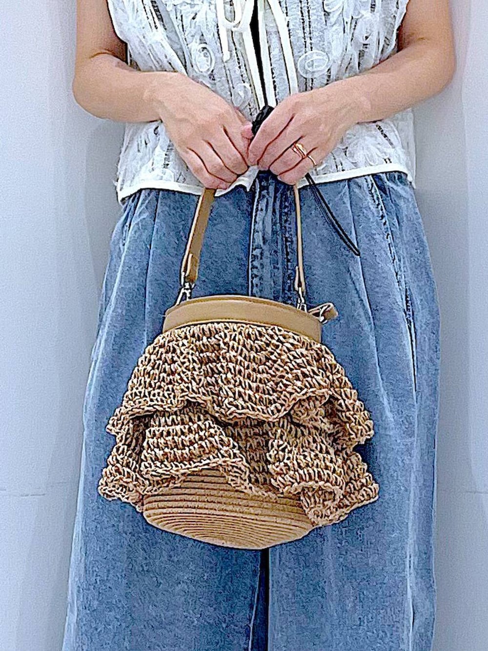 ベージュ系のショルダーバッグ、ブルー系のデニムパンツ、ベージュ系のベストを着用したレディースの夏コーディネートの9枚目の写真
