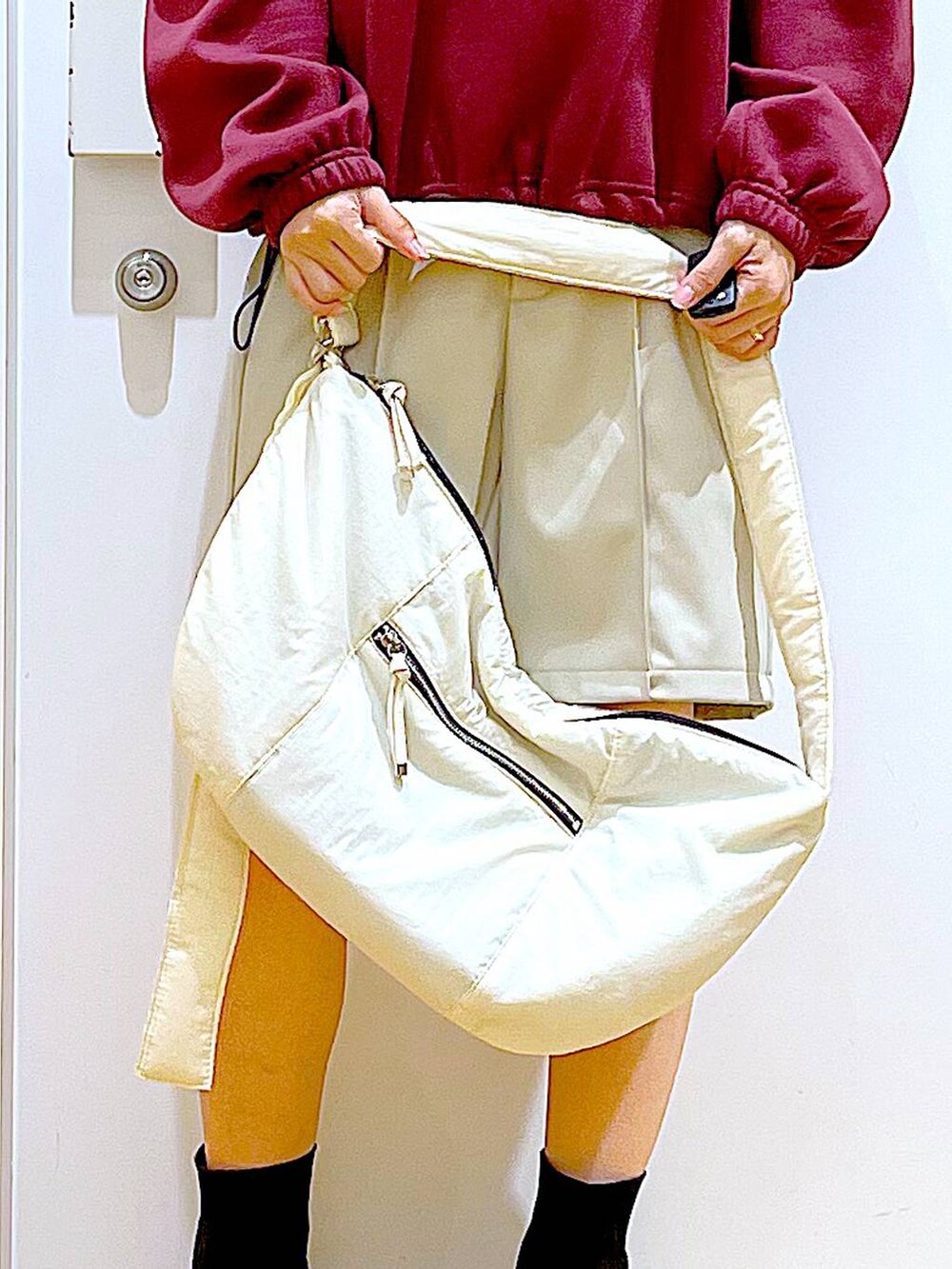 ホワイト系のショルダーバッグ、ブラック系のブーツ、レッド系のスウェットを着用したレディースの冬コーディネートの9枚目の写真