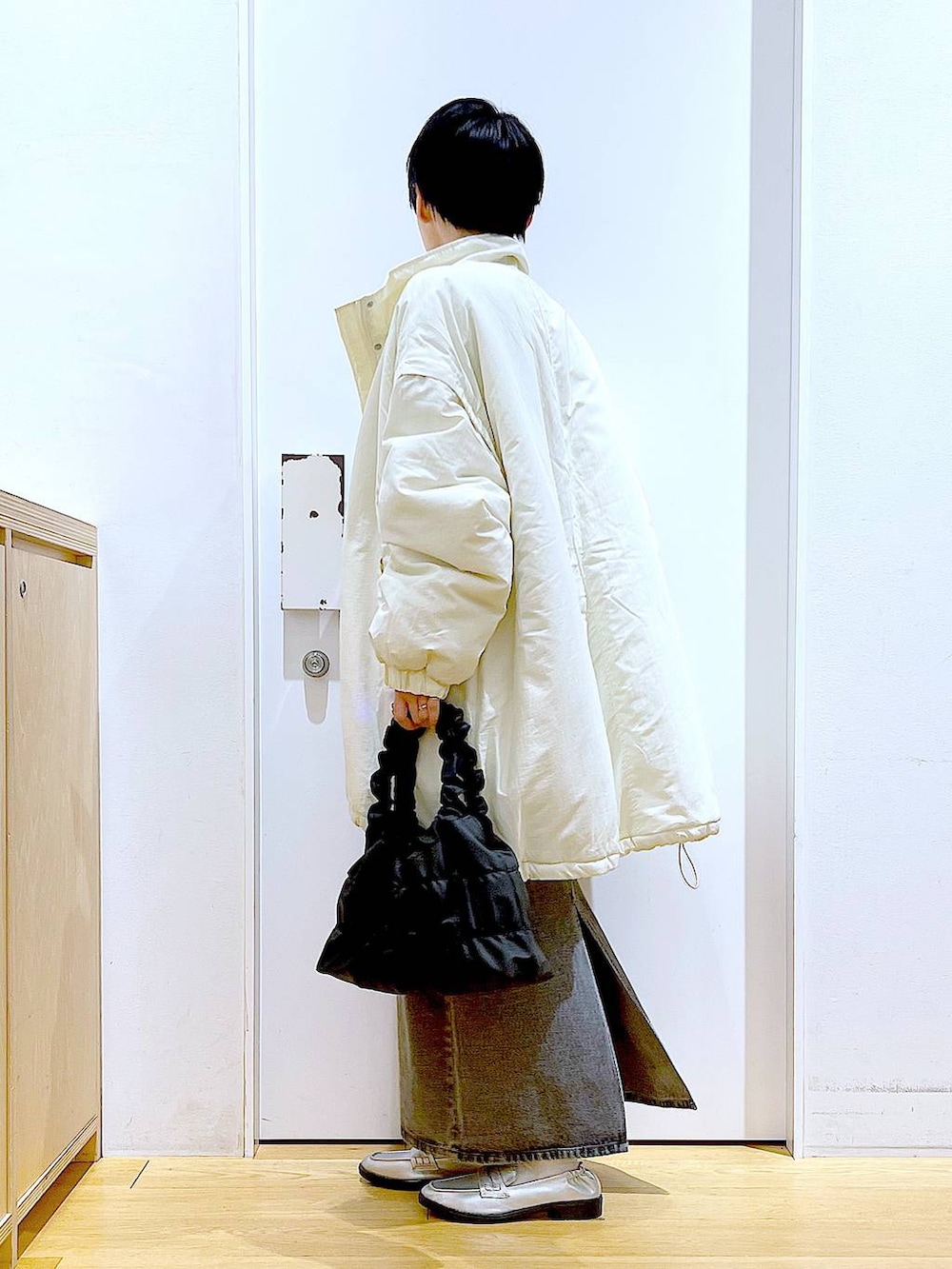 シルバー系のローファー、ホワイト系のその他アウター、ブラック系のショルダーバッグを着用したレディースの冬コーディネートの3枚目の写真