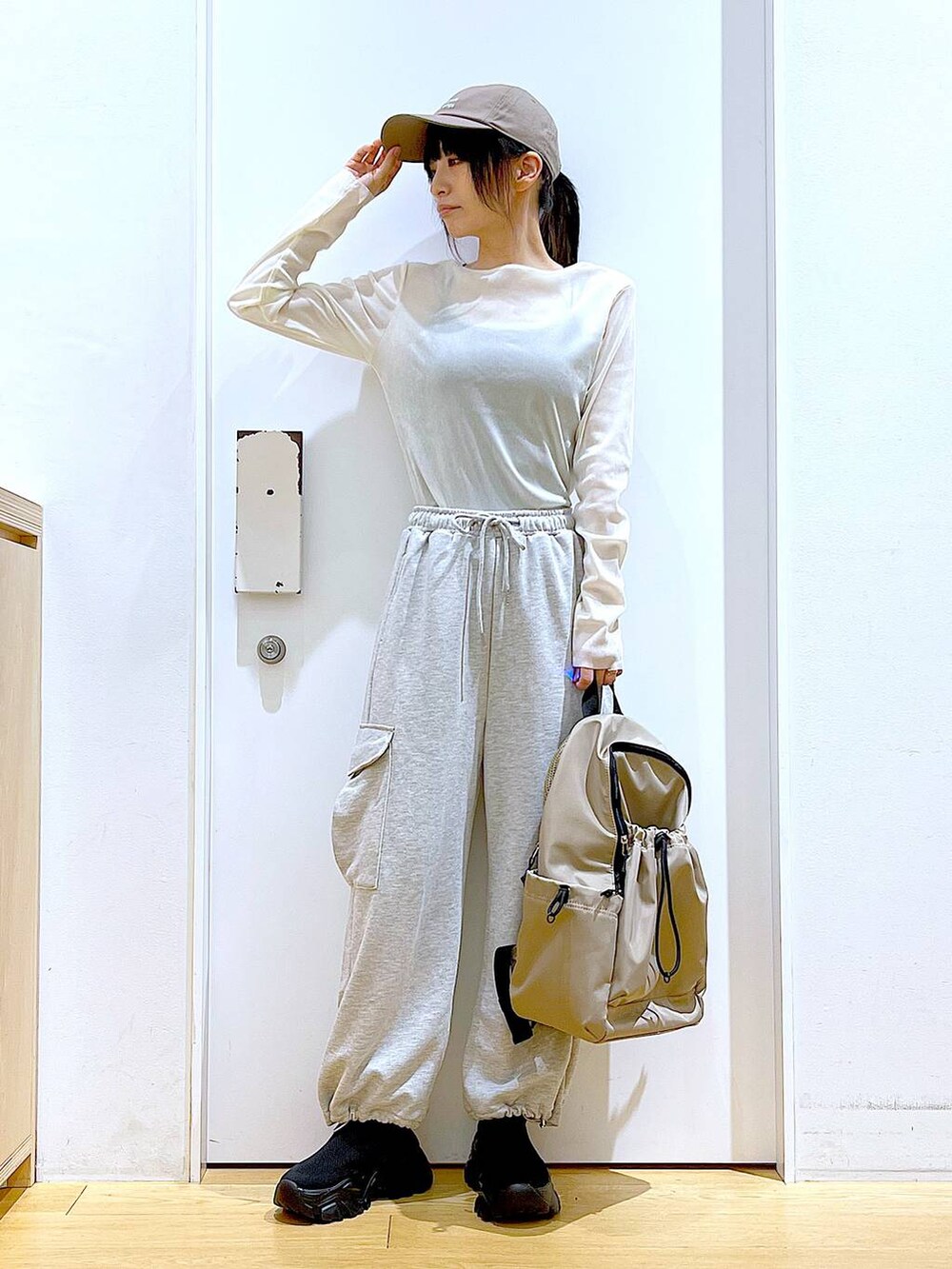 グレー系のスウェットパンツ、ベージュ系のバックパック/リュック、ブラック系のスニーカーを着用したレディースの春コーディネートの2枚目の写真