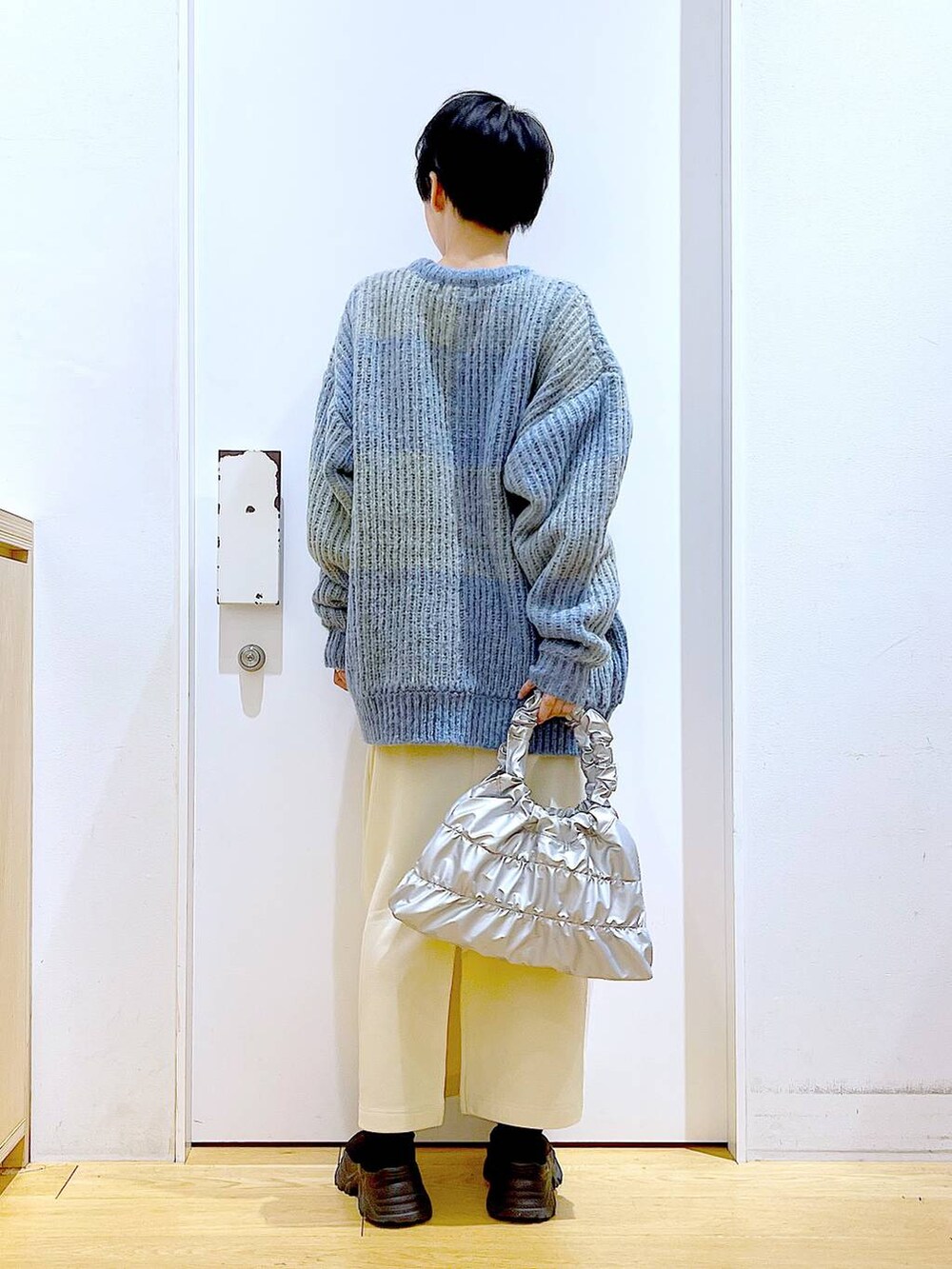 ブルー系のニット/セーター、ブラック系のブーツ、シルバー系のショルダーバッグを着用したレディースの冬コーディネートの5枚目の写真