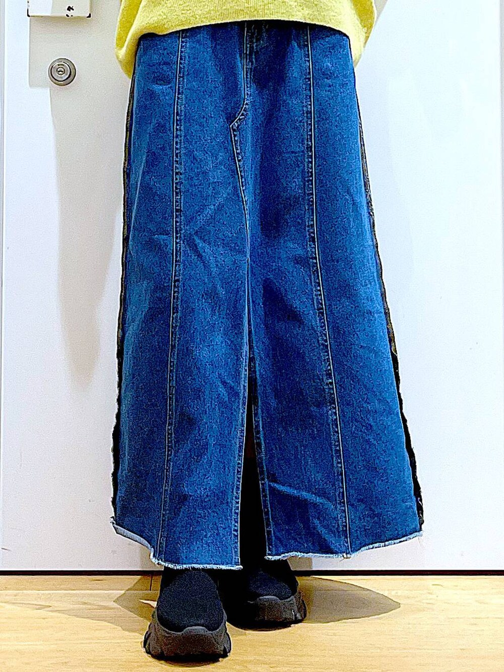 イエロー系のニット/セーター、ブルー系のデニムスカート、ベージュ系のショルダーバッグを着用したレディースの冬コーディネートの8枚目の写真