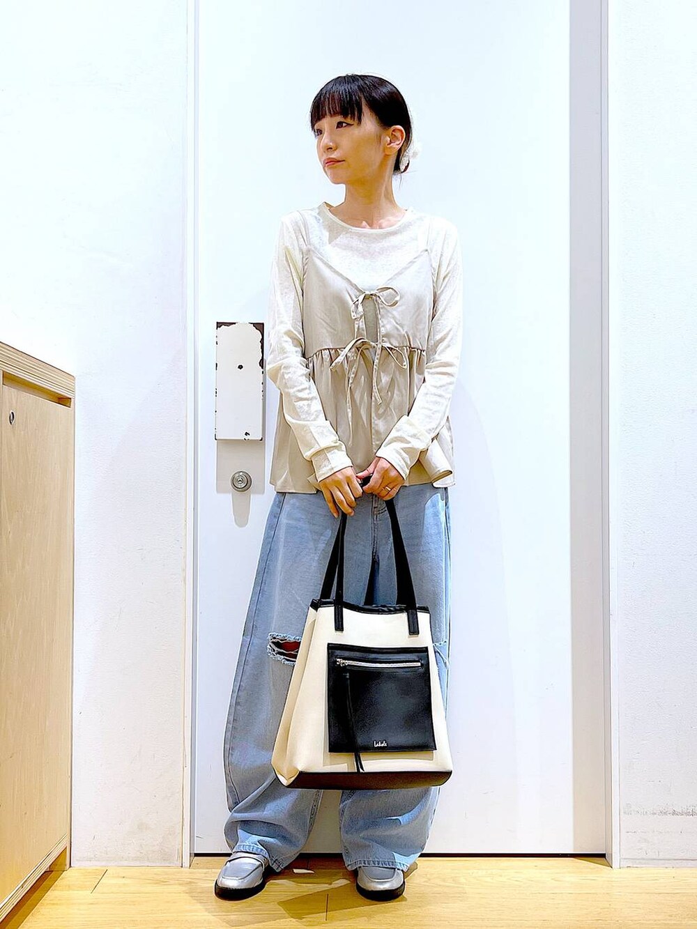 ブルー系のデニムパンツ、シルバー系のローファー、ホワイト系のトートバッグを着用したレディースの秋コーディネートの2枚目の写真