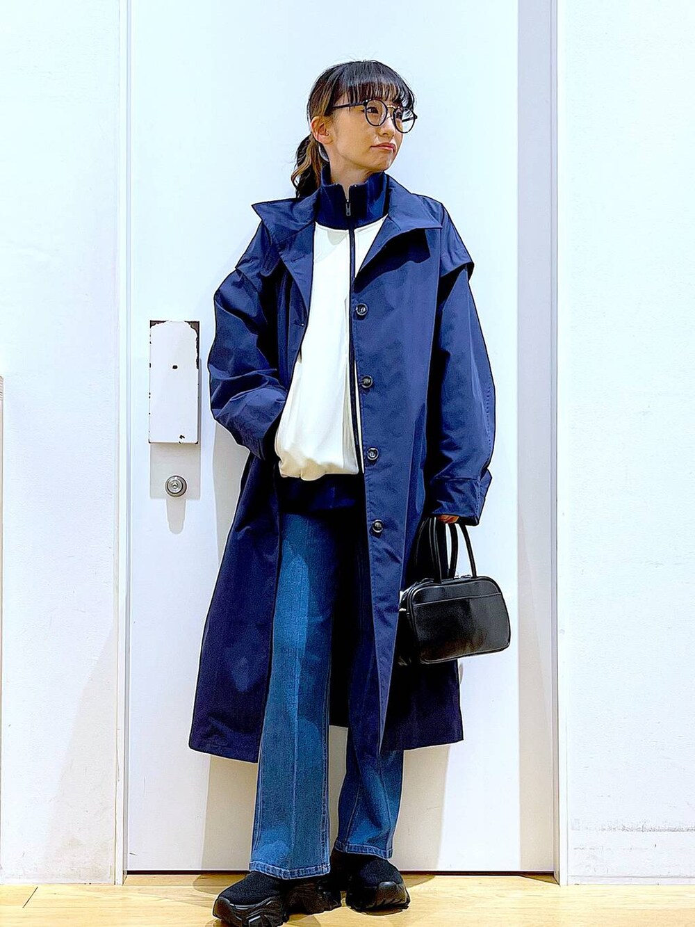 ブラック系のショルダーバッグ、ブルー系のデニムパンツ、ブルー系のその他アウターを着用したレディースの冬コーディネートの2枚目の写真