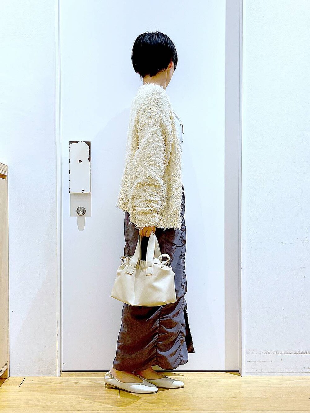 グレー系のスカート、ホワイト系のショルダーバッグ、ホワイト系のパンプスを着用したレディースの春コーディネートの4枚目の写真