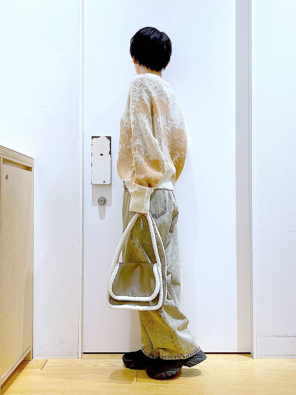 ブラック系のブーツ、ベージュ系のショルダーバッグ、ベージュ系のデニムパンツを着用したレディースの冬コーディネートの3枚目の写真