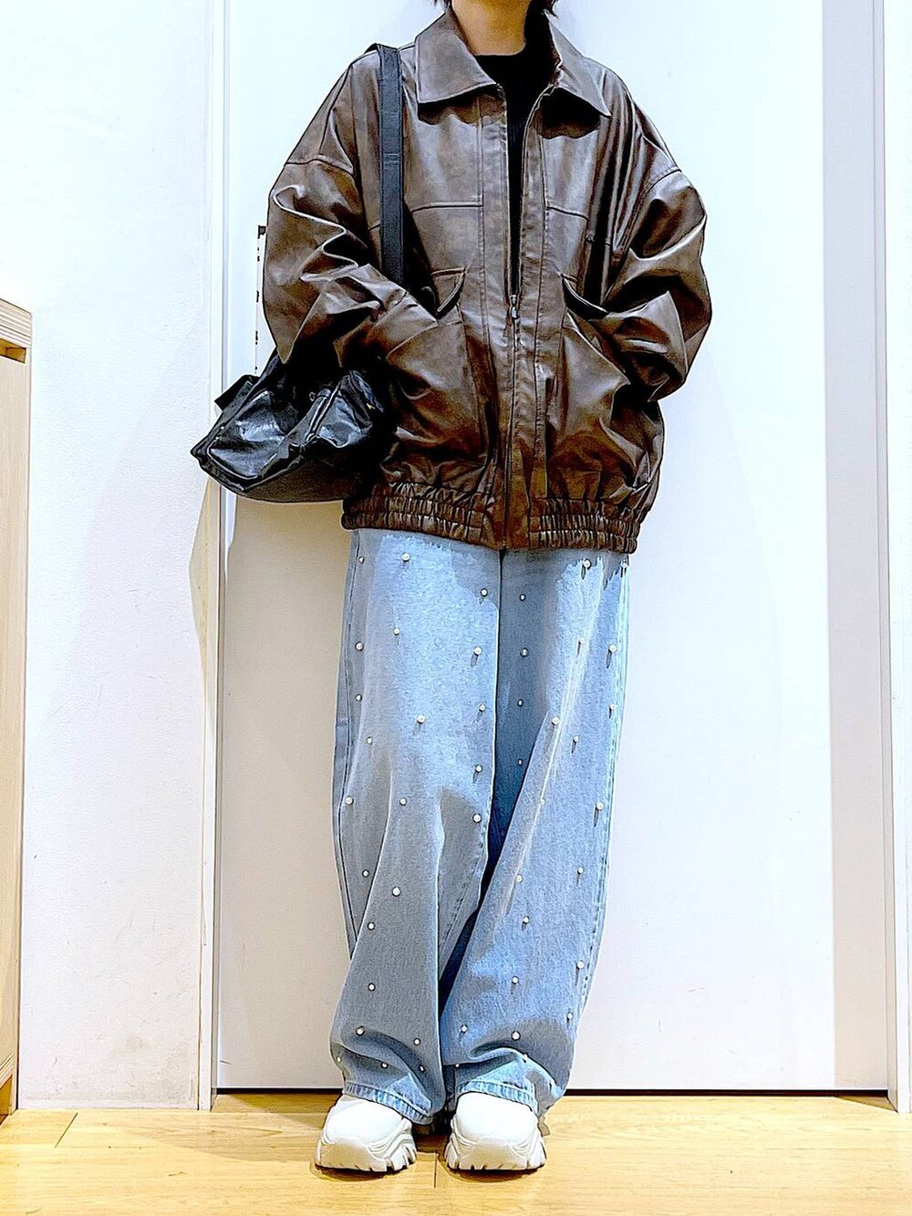 ブラウン系のブルゾン、ベージュ系のブーツ、ブルー系のデニムパンツを着用したレディースの秋コーディネートの6枚目の写真