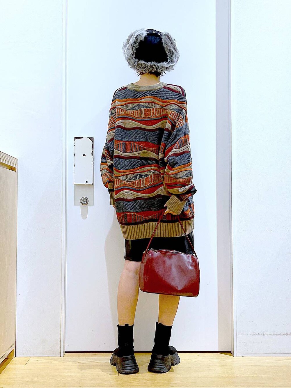 レッド系のショルダーバッグ、ブラック系のブーツ、ブラック系のその他パンツを着用したレディースの冬コーディネートの5枚目の写真