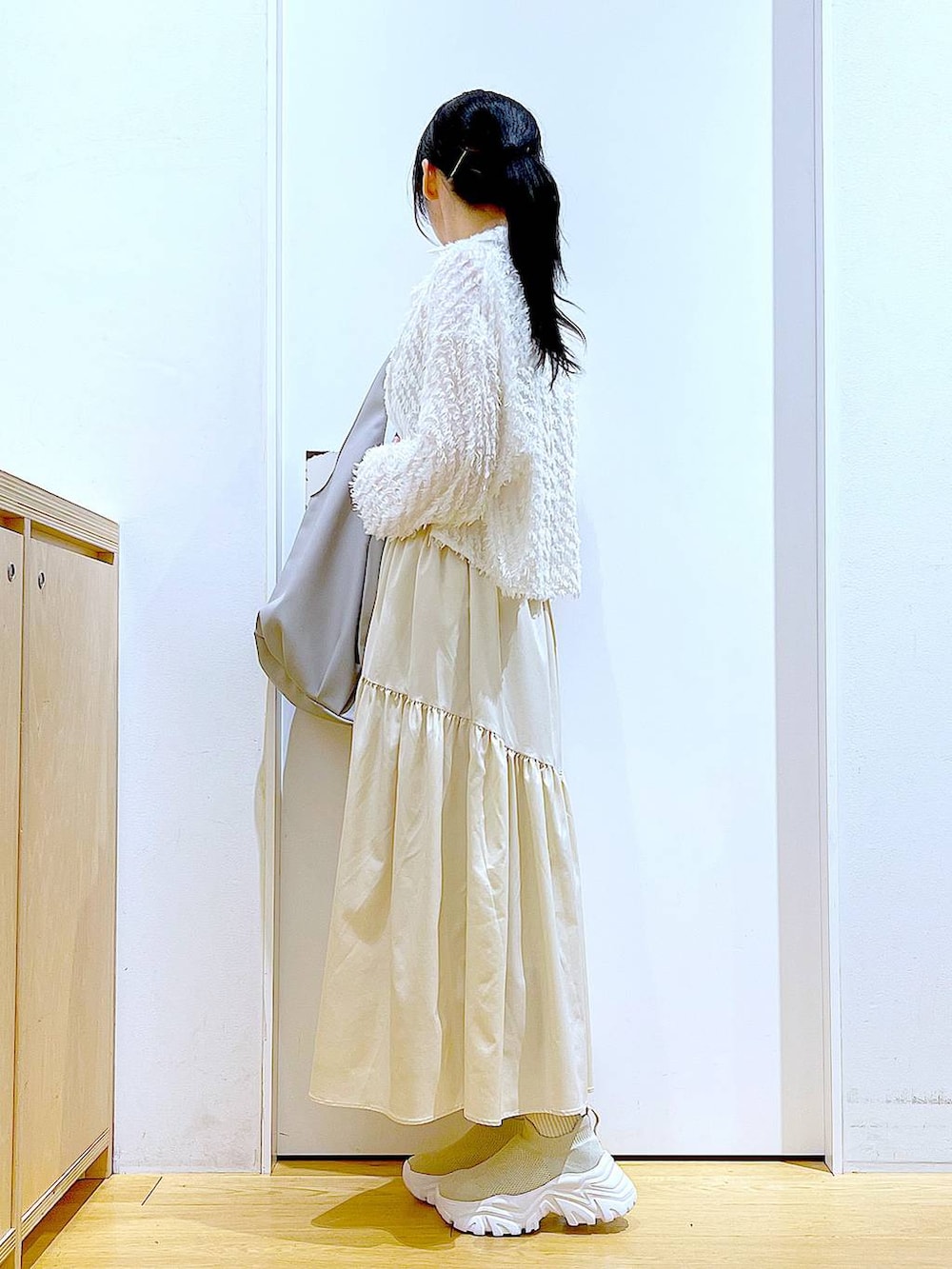 グレー系のトートバッグ、ホワイト系のシャツ/ブラウス、ベージュ系のスニーカーを着用したレディースの春コーディネートの3枚目の写真