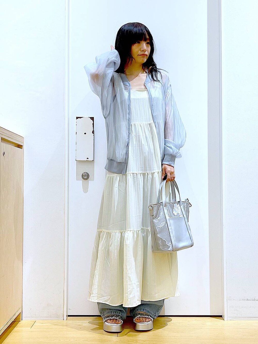ブルー系のデニムパンツ、シルバー系のトートバッグ、シルバー系のサンダルを着用したレディースの夏コーディネートの2枚目の写真