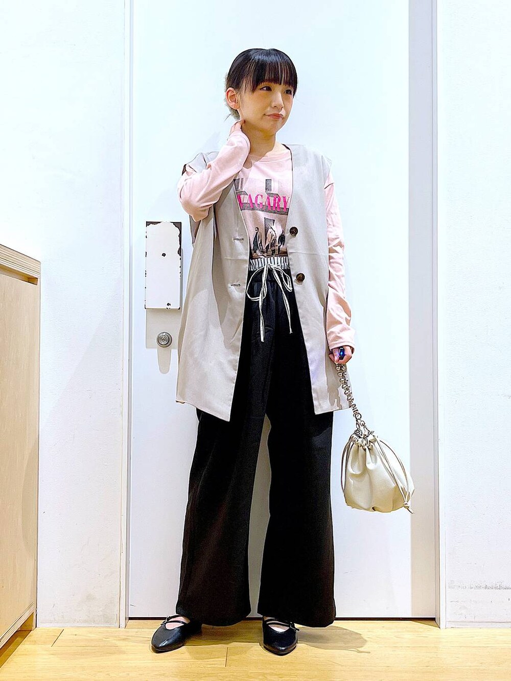 ベージュ系のショルダーバッグ、ブラック系のパンプス、ベージュ系のベストを着用したレディースの秋コーディネートの2枚目の写真