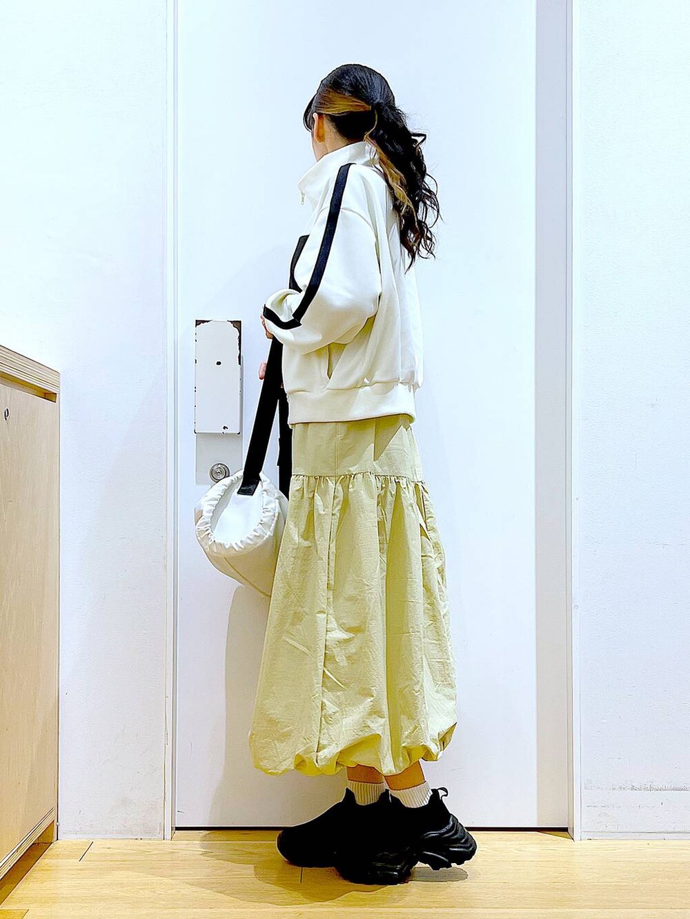 ベージュ系のブルゾン、ベージュ系のスカート、ホワイト系のショルダーバッグを着用したレディースの冬コーディネートの3枚目の写真