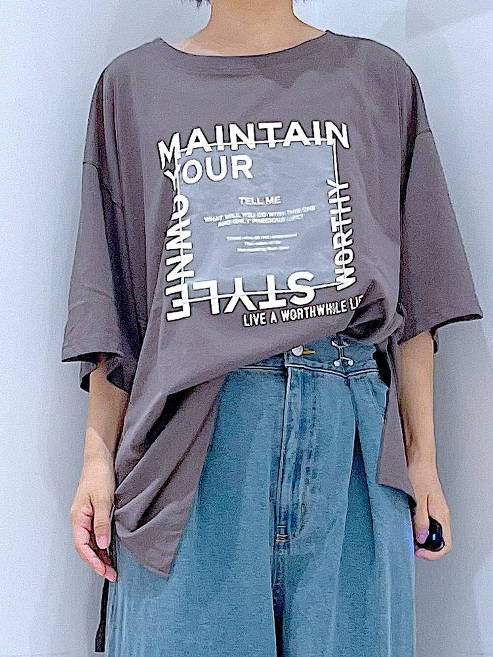 ブラック系のショルダーバッグ、ブラック系のスニーカー、ブルー系のデニムパンツを着用したレディースの秋コーディネートの7枚目の写真