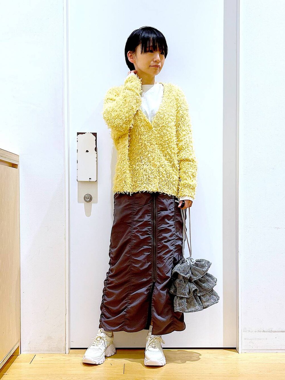 シルバー系のショルダーバッグ、グレー系のスカート、ホワイト系のスニーカーを着用したレディースの春コーディネートの2枚目の写真