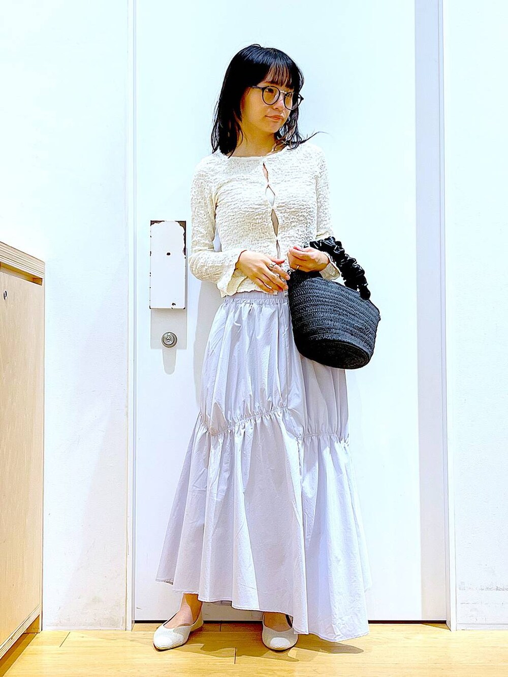 ホワイト系のカーディガン/ボレロ、イエロー系のニット/セーター、ホワイト系のパンプスを着用したレディースの春コーディネートの2枚目の写真