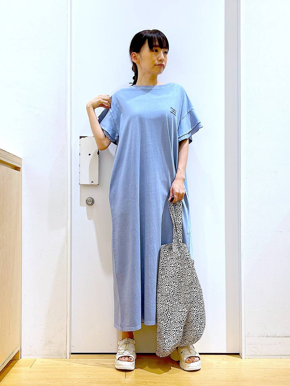 ホワイト系のサンダル、ベージュ系のトートバッグ、ブルー系のワンピースを着用したレディースの夏コーディネートの2枚目の写真