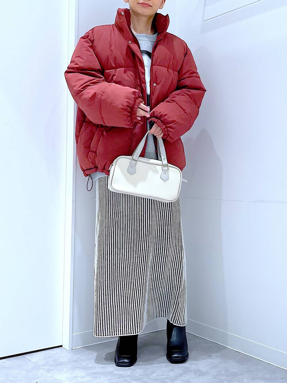 ブラウン系のブルゾン、ベージュ系のスカート、ブラック系のブーツを着用したレディースの冬コーディネートの6枚目の写真