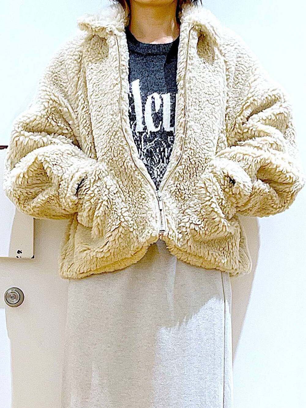 ホワイト系のブルゾン、ブラック系のブーツ、ベージュ系のスカートを着用したレディースの冬コーディネートの7枚目の写真