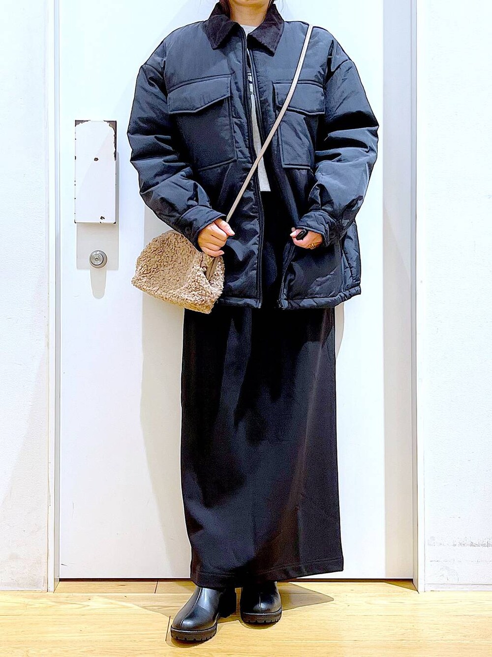 ブラック系のブルゾン、ブラック系のブーツ、ブラウン系のクラッチバッグを着用したレディースの冬コーディネートの6枚目の写真