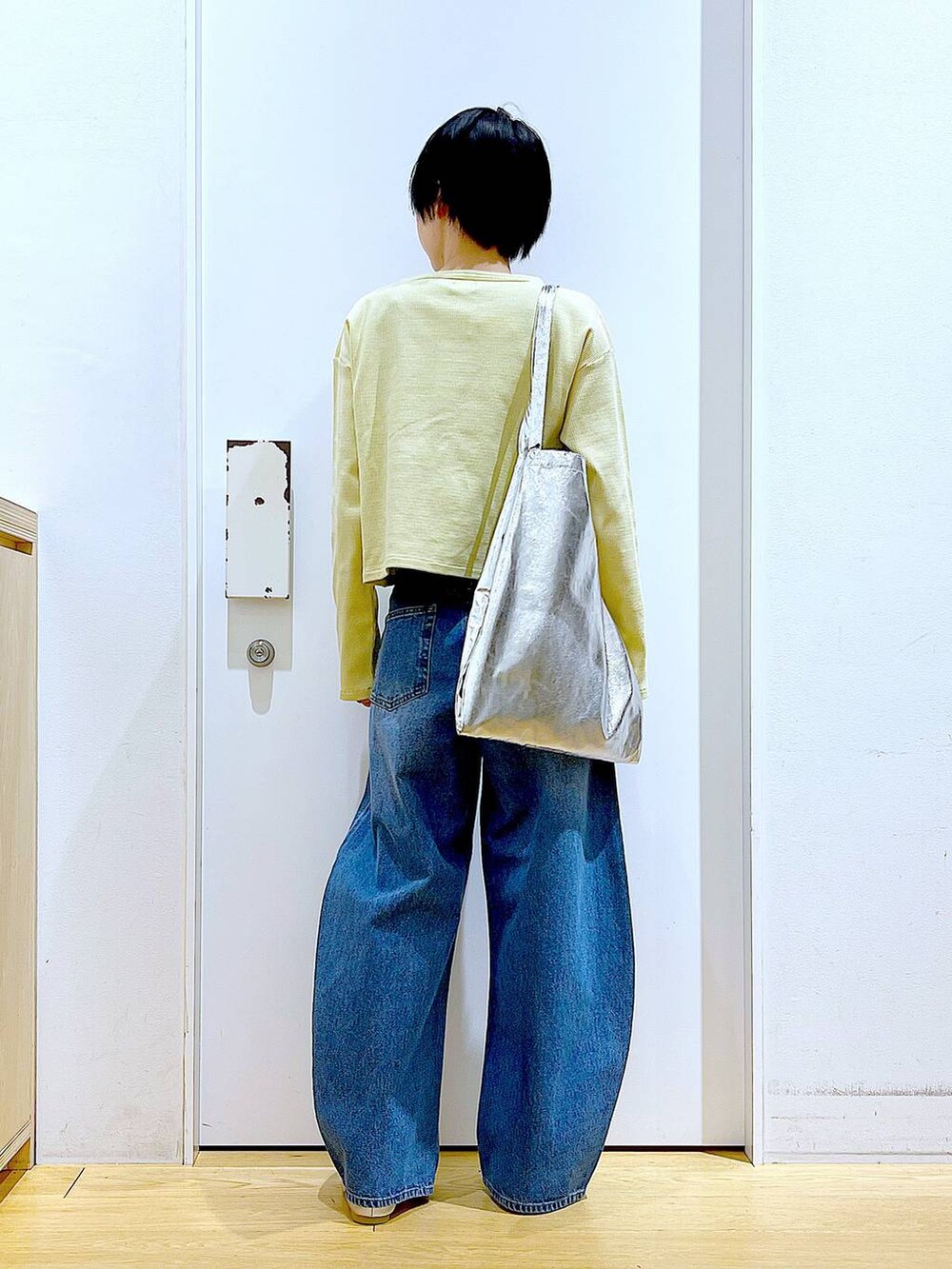 シルバー系のトートバッグ、ブルー系のデニムパンツ、シルバー系のパンプスを着用したレディースの春コーディネートの5枚目の写真