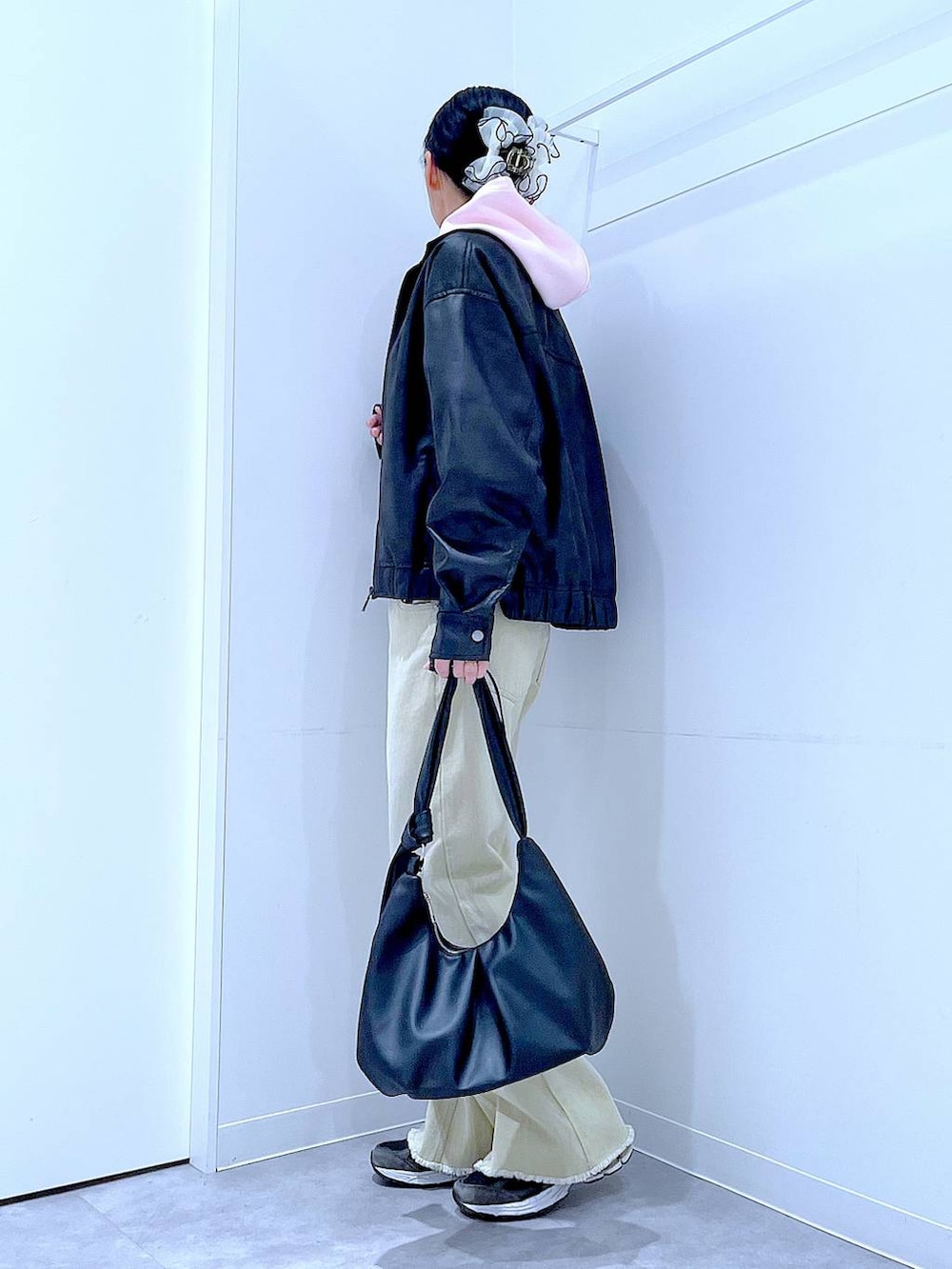 ブラック系のブルゾン、ベージュ系のデニムパンツ、ピンク系のパーカーを着用したレディースの冬コーディネートの3枚目の写真