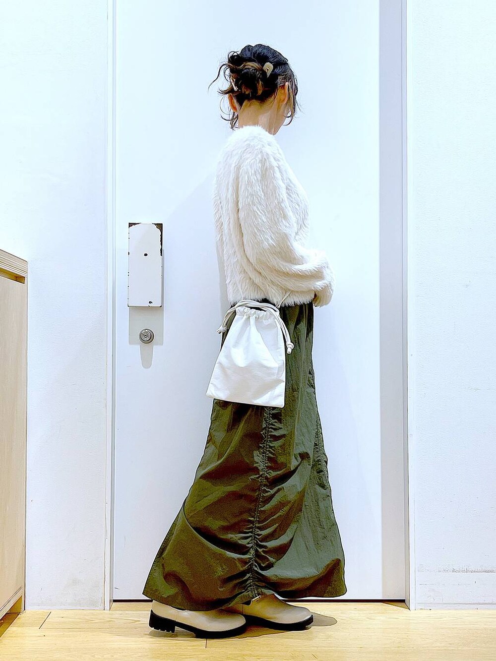 ベージュ系のブーツ、ベージュ系のニット/セーター、グリーン系のスカートを着用したレディースの冬コーディネートの4枚目の写真